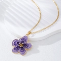 Gros plan d'un pendentif fleur en émail violet avec bords dorés et chaîne fine - Violet