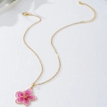 Vue détaillée du pendentif fleur en dégradé rose avec chaîne dorée et fermoir mousqueton - Rose