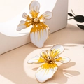Orecchini a fiore con smalto bianco giallo e dettagli dorati su un supporto espositivo bianco - Orecchini a Fiore Bianchi