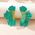 Macro shot of 3D floral earrings with vibrant teal and yellow enamel on a white stand - Green Earrings
