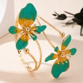Close-up of golden open cuff bracelet featuring green and yellow enamel flower petals - Green Flower Open Bracelet