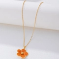 Close-up of golden necklace with orange enamel flower pendant on a clean white background - Necklace