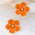 Close-up of orange enamel flower stud earrings with golden trim and retro floral design - Stud Earrings