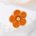 Gros plan détaillé d'une bague fleur en émail orange avec bordure dorée sur socle - Bague