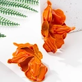 Detailansicht großer oranger Blumenohrringe mit glänzender Lackierung auf Steintextur - Orange