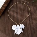 Close-up of golden twist chain and matte white 3D orchid petal pendant on wood background - Necklace / White