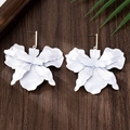 Macro detail of matte white blooming orchid earrings with golden studs on wooden surface - Stud Earrings / White