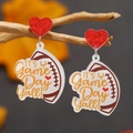 Macro shot of acrylic football earrings featuring red glitter hearts on rustic wood - It's Game Day Yall Style (WEH4519)