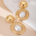 Detailed close-up of retro gold geometric earrings with pearls on silk background - White