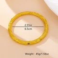 Gedetailleerd overzicht van de gouden armband met gravures en smaragdgroene edelsteenaccenten - Goud