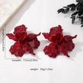 Close-up showing dimensions of large dark red flower earrings on a textured background - Burgundy
