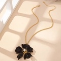 Détail du pendentif fleur en émail vintage avec perle sur une chaîne torsadée dorée - Noir