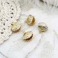 Macro detail of 18K gold plated shell charms with sparkling zircons on white lace background - White Zirconia Scallop