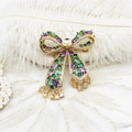 Detail of a luxury gold bow brooch with emerald and purple stones on lace - 44*55mm / Colorful Zircon Bowknot Tassel Style (G0537)