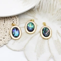 Three oval abalone shell pendants with golden bead edge on elegant white lace background - Abalone Shell Oval