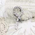 Broche serpent en argent avec zircons blancs sur un fond de plumes blanches douces - Serpent