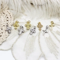 Dettaglio macro di otto ciondoli a croce in oro 18 carati e argento su pizzo bianco - Croce a Foglia / Oro 18K