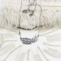 Vue macro d'un collier avec pendentif plume argenté orné de zircons blancs brillants - Plume Argentée