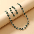 Macro detail of emerald rhinestone necklace and drop earrings set in silver finish - Green