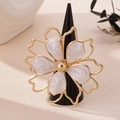 Macro detail of a golden flower ring with white marble enamel and hollow petals - White Ring