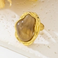 Detailed macro view of an irregular brown resin stone on a hammered gold-tone ring band - Amber