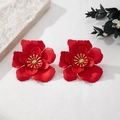 Gros plan détaillé d'une boucle d'oreille fleur rouge mat avec cœur doré et cristal - Rouge