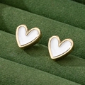 Minimalist heart-shaped gold studs with white enamel on green velvet tray - White