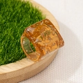Close-up of translucent amber resin ring with gold foil flakes on decorative grass - Amber