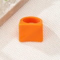 Close-up of bright orange resin geometric square ring on textured woven background - Orange
