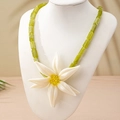 Macro view of a large white lily pendant with yellow center and green beaded resin necklace - Necklace