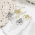 Detailed view of 18k gold and silver bow pendants with ribbons on white lace fabric - Elongated Bowknot / 13*18.2mm / Gold