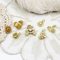 Detail shot of golden floral charms and clover pendants on white lace background - Leftmost Six-petal Flower 10*13mm