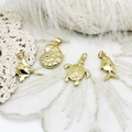 Detailed close-up of 18K gold marine pendants featuring stingray, nautilus and turtle charms - Manta Ray