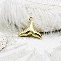Detailed view of an 18K gold-plated whale tail pendant on white lace and feather background - Fish Tail