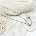 Collana a catena box argentata con chiusura a moschettone su sfondo di pizzo e piume - scatola catena