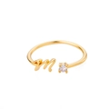 Detail eines verstellbaren Goldrings mit Schreibschrift M und funkelndem Zirkon - Buchstabe M