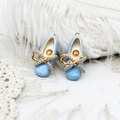 Macro view of light blue ballet shoe pendant with gold bow and sparkling crystal inlay - Blue Ballet Shoes