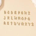 Golden alphabet pendant necklace set with pavé crystals on a textured beige surface - Letter B