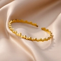Close-up of golden stainless steel open bracelet with textured bead dot design on silk - Silver-like Texture / Gold