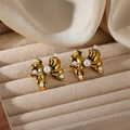 Primer plano de pendientes de lazo dorado con perlas blancas en bandeja de terciopelo - Pendientes de Botón con Lazo y Múltiples Perlas (G12305594)