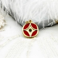 Macro view of gold plated round charm with red enamel motifs and central star pattern - Coin
