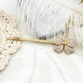 Vue macro d'une barrette à cheveux nœud dorée 18K et cristaux sur dentelle élégante - Barrette à nœud