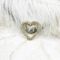 Macro shot of gold-plated heart pendant with micro-set zircons on white feather background - Micro-paved Heart