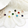 Macro shot of colorful faceted gemstone pendants with gold prong settings and jump rings - Round Pendant / Yellow