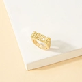 Anillo dorado minimalista con la palabra Bride sobre un fondo geométrico de tonos suaves - Estilo de Letra BRIDE (J273-1) / Dorado