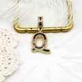 Vue macro du pendentif lettre Q plaqué or 18k avec zircons arc-en-ciel et plumes blanches - S1 / Lettre Q