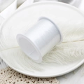 Macro shot of transparent elastic beading thread roll on white spool for DIY jewelry making - Non-Elastic 0.25 Fishing Line