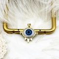 Macro view of 18K gold evil eye pendant with blue eye and zircons on lace background - Little Eyes