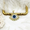 Detail of 18K gold evil eye pendant with blue core on elegant white lace background - Eye