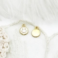 Detailed view of 18K gold plated smiling face charms with white enamel on lace background - Smiley Face